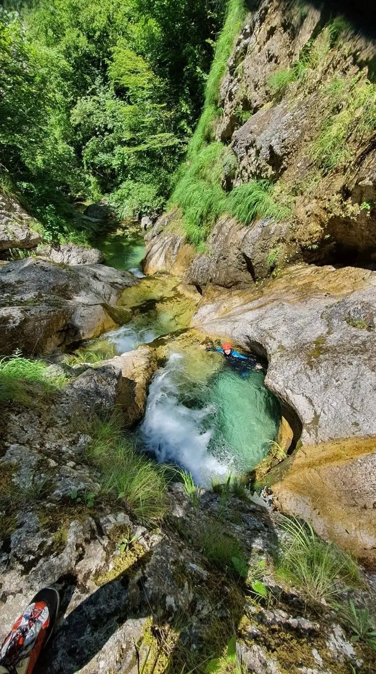 A guide floating in a clear turquoise canyon pool